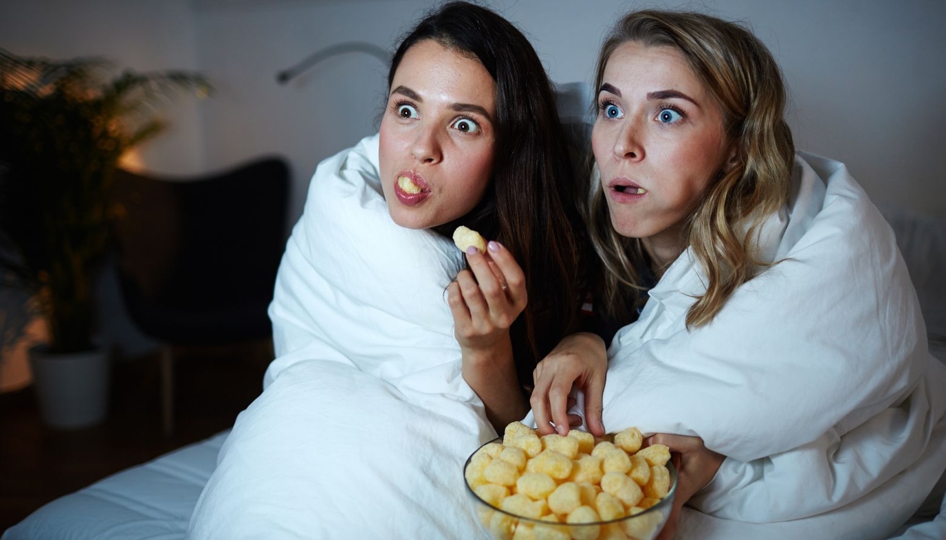 girls watching a movie and eating popcorn