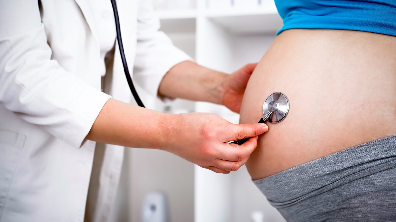 doctor listening to pregnant woman's belly