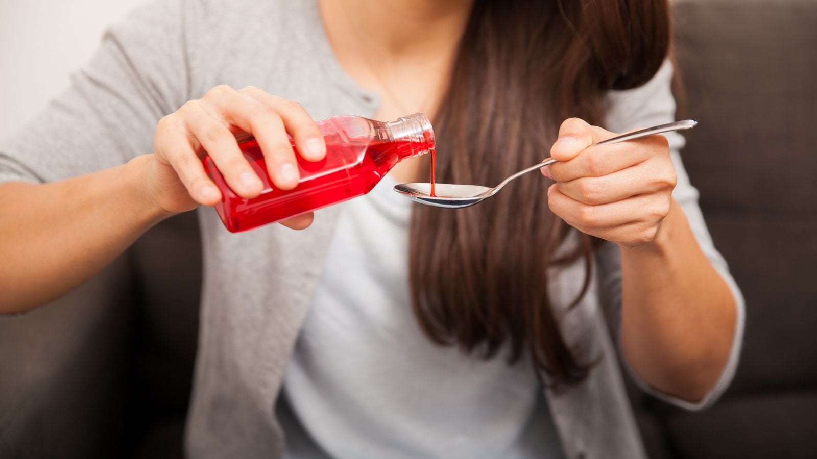 woman pouring cough syrup into spoon