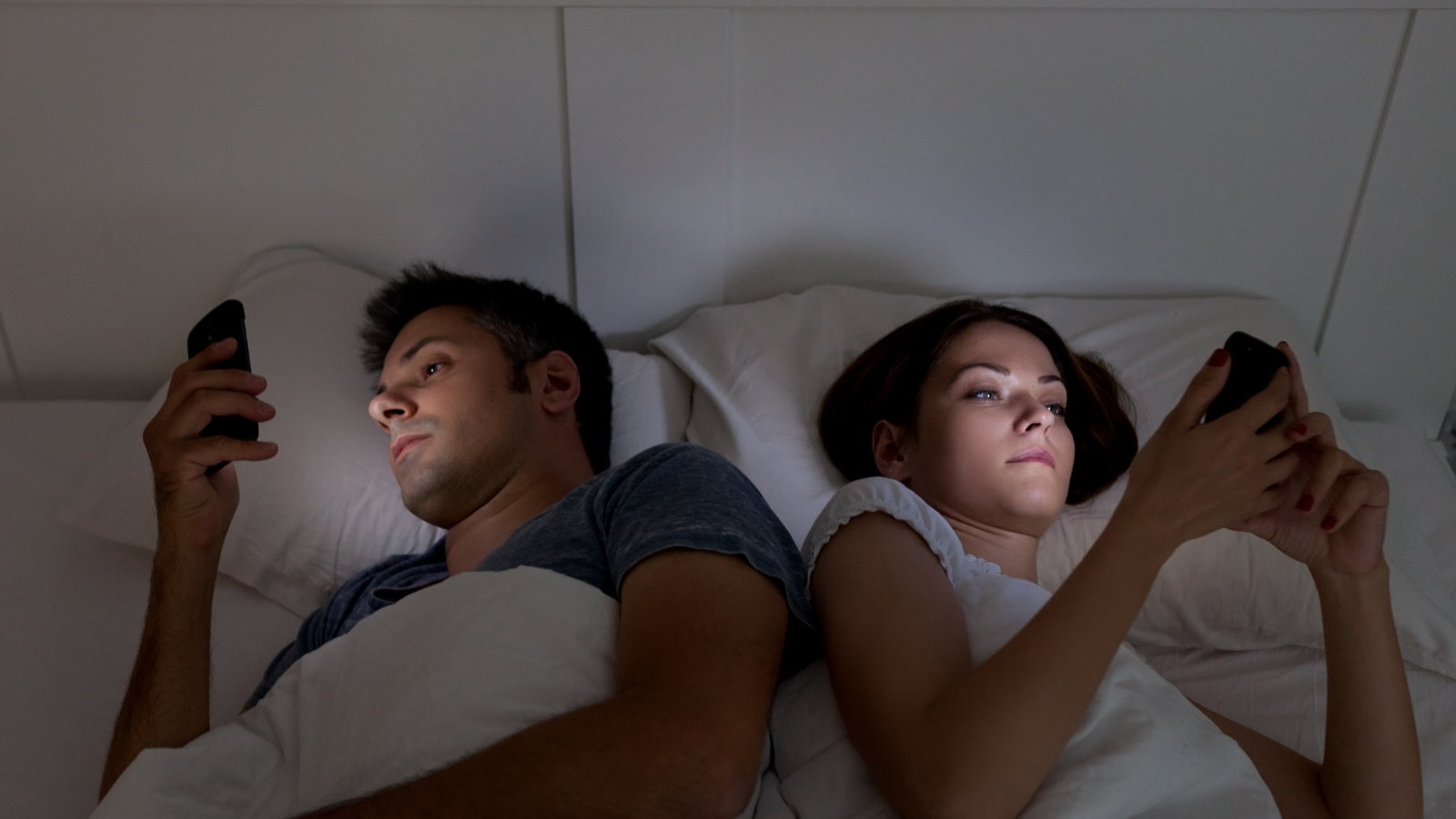 couple in bed using cell phones