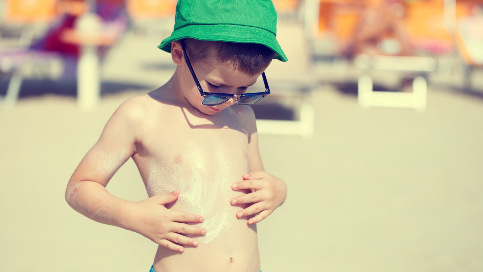 boy at the beach applying sunscreen