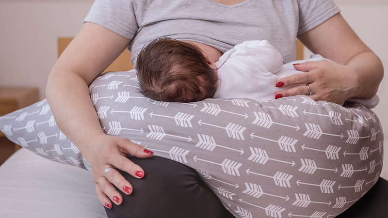 Mother breastfeeding baby on pillow