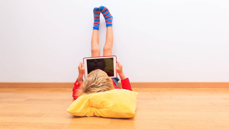 boy laying on the floor playing on a tablet