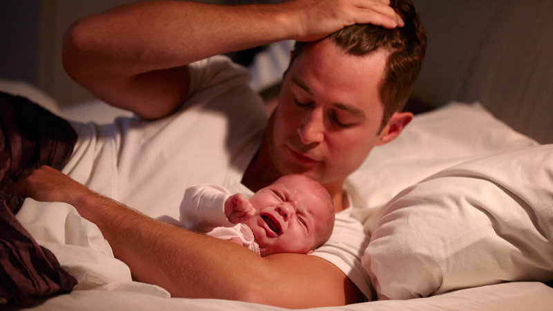 Father in bed with crying baby