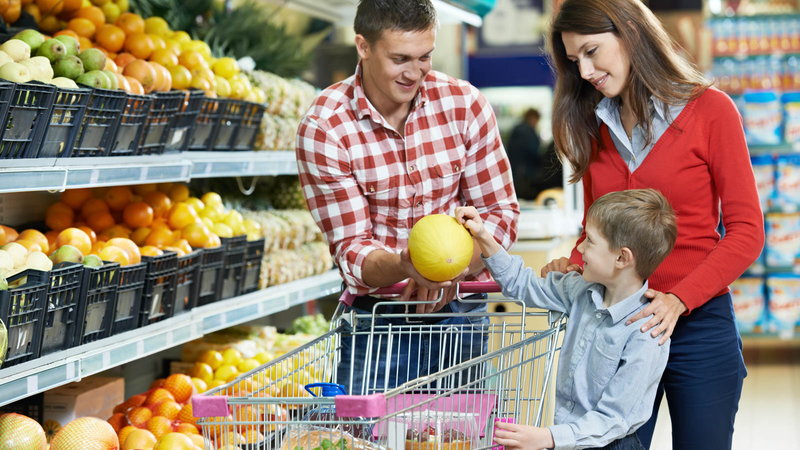 parents letting child pick out fruit at the grocery store