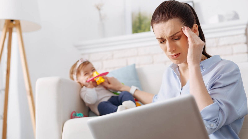 tired mother working on computer near her baby