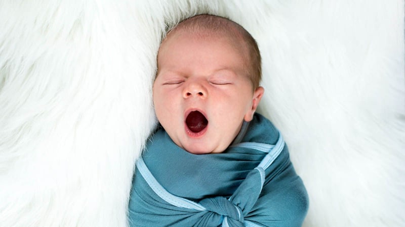 swaddled baby yawning