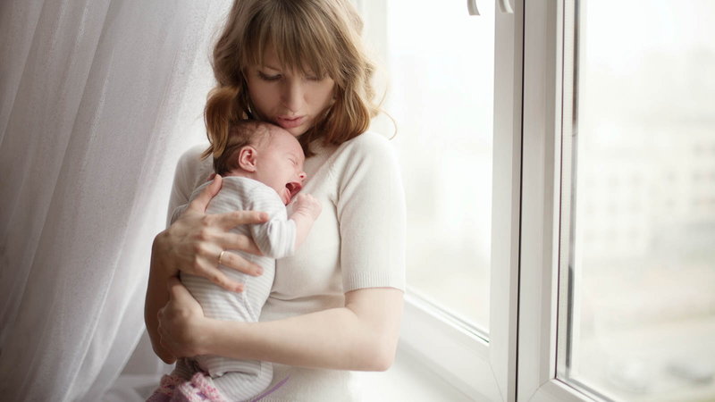 Mother holding baby next to window