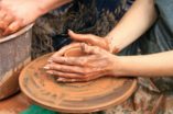 close up of hands drenched in clay while doing pottery work