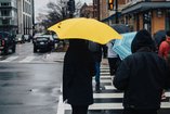 A man holds his wife on his back in the rain, and they smile.