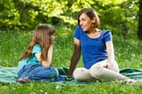 mom and daughter sitting on picnic blanket talking
