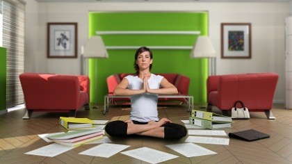 A mom meditating while surrounded by paper work.