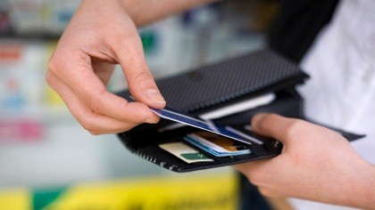 A woman pulls a credit card from her wallet.