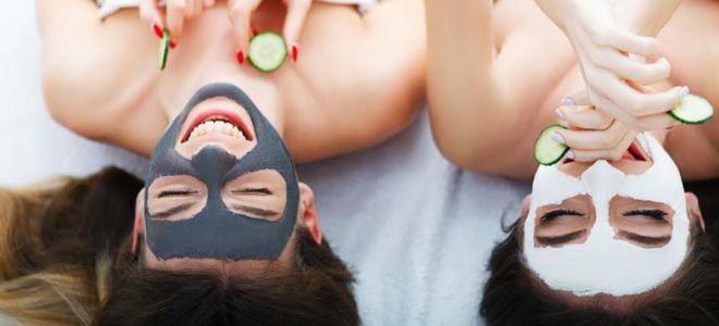 smiling women with beauty masks and cucumber slices