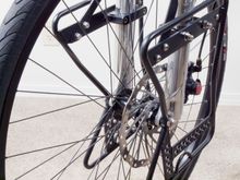 Custom low rider racks built from old Axiom outer frame. Mounts machined from Delrin and hand fitted to avoid compressing the fork casting. Front axle and 'V' brake mounts carry most of the load. Bombproof (but not tested with a bomb yet).