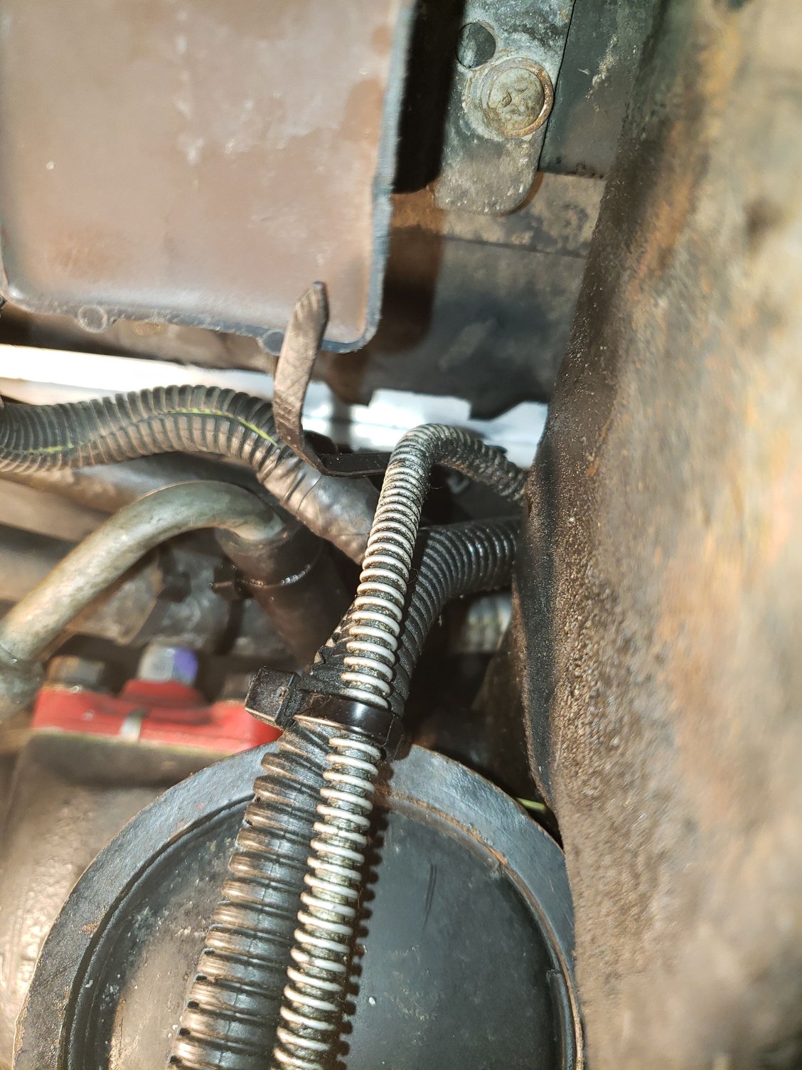 This view is looking up and to the rear on the driver side. The front of the steering gear is in the lower half. A the bottom of the radiator is the  zip tie that secures the lower fan shroud to the radiator.