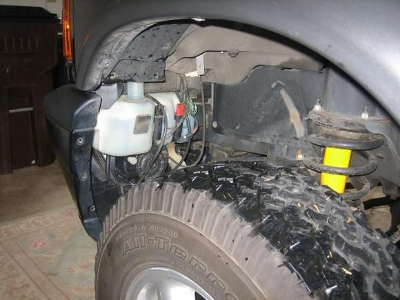 Pull the front valance of the inner well out and the washer fluid reservoir is easily accessed. Gotta disconnect the motors and fog light harnesses while you're in here.