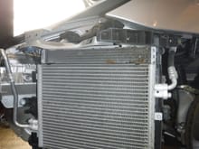 AC condenser (this is driver's side) is in front of the radiator, with electric fan behind that.  Debris you see at top of radiator is not accessible with bumper in place.