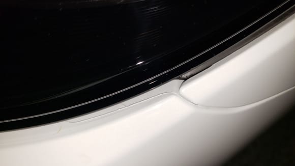 See the plastic looking edge right before the painted bumper meets the headlamp.