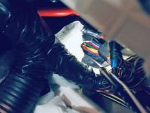 White metal coat-hanger entering a firewall grommet in the passenger-side footwell of an '06 LHD DB9 Volante