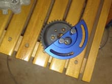 sprocket with tool attached.  The sprocket will be inside the chain cover.  The outside lip of the blue tool bolts onto the chain cover using the bolts that held the access cover on, the long headed bolts screw into the sprocket.