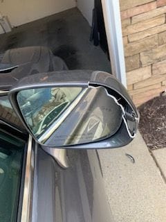Damaged mirror with part lying in driveway