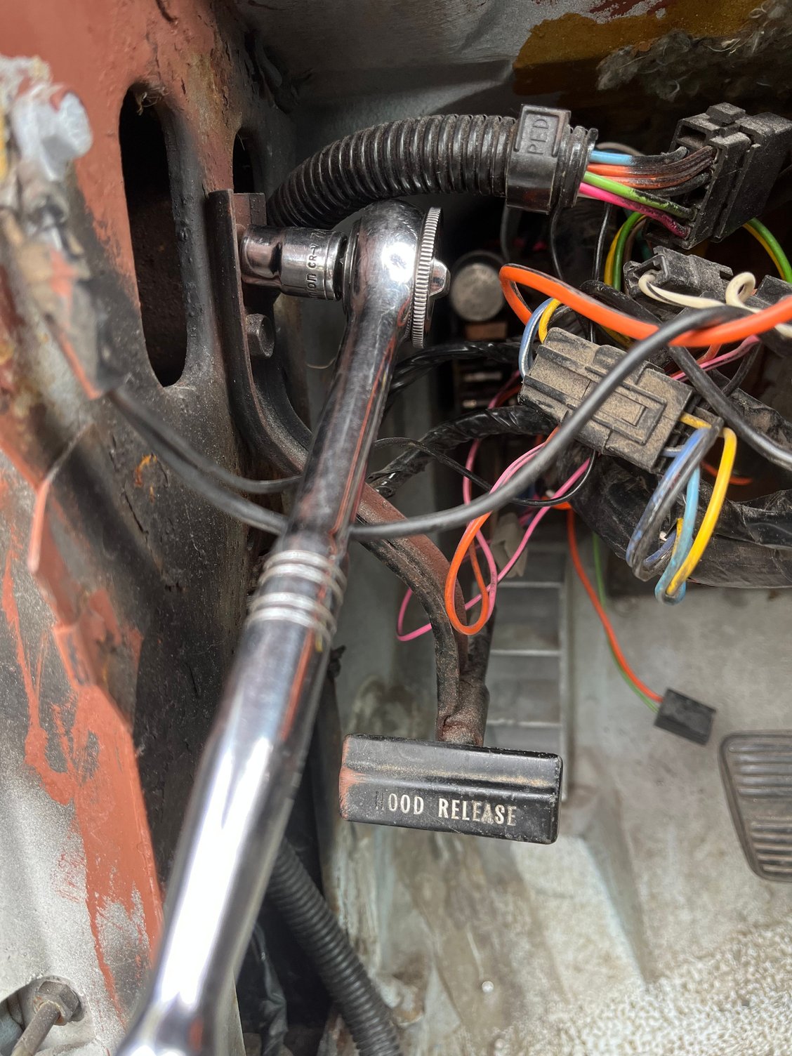 With the dash out of the car, it�s easier to push wires out of the way and remove the hood release bracket, affording better access to the fuse box on the driver�s side firewall.