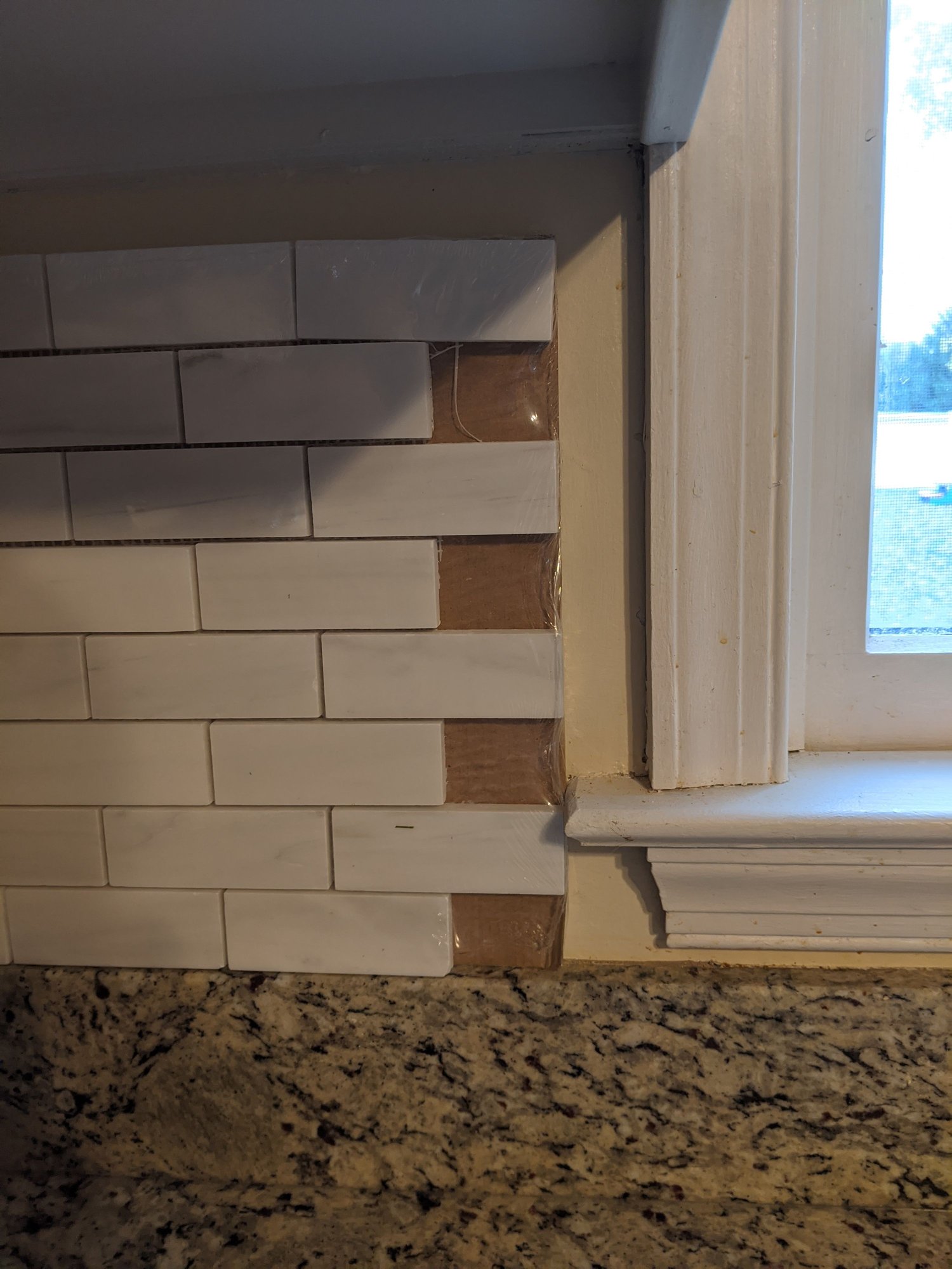 Proper way to finish this tile wall to the floor?