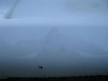 I believe this is from a garbage can that blew into the bumper on a windy day.  Wax might take this off.  This is right below where the license plate mounts.