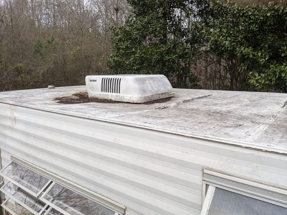 Roof seems to be sheet metal coated with mastic/roofing tar and then painted
