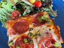 A slice of leftover Detroit style pizza and salad for lunch. 