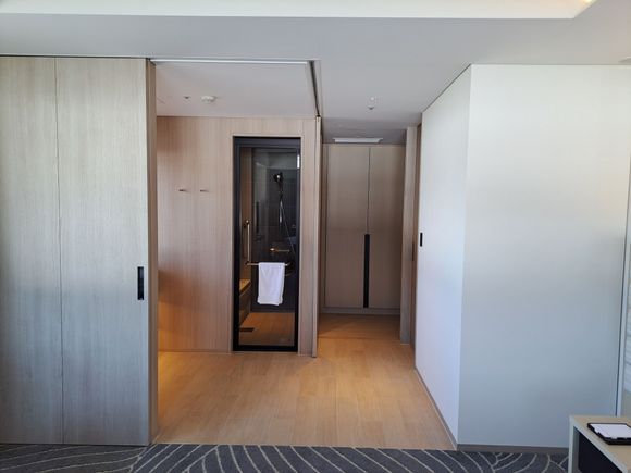 Bathroom from the bedroom. Bathroom sliding doors fully open. Toilet to the right . Cupboard at the far end with entrance door to the right out of sight