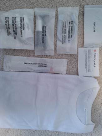 Contents: XL plain white t shirt; dental kit;  towelette; charging cable (nice touch!); shaving kit; moisturizer, fabric freshener & deodorant.