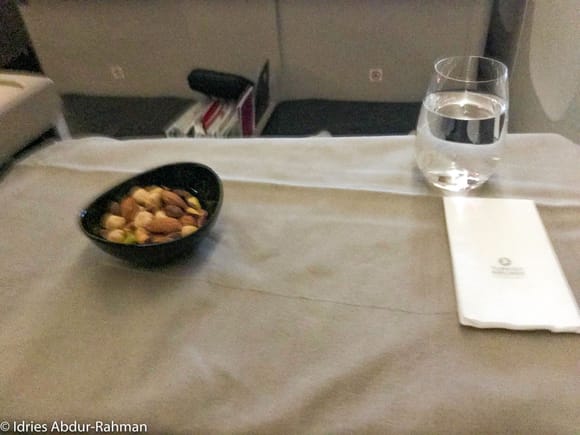 As I kicked back and put my seat into recline mode, the cabin crew set the tray table with linens and distributed mixed nuts to get the dinner service started.