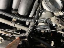 Finger pointing at injector wiring.  Not sure how to disconnect this so can lift manifold up.
