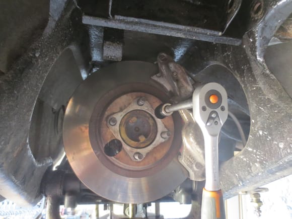 Access with exhaust disconnected. showing caliper in the process of being unbolted. Note the lower wishbone has to be swung right down to get the disc off