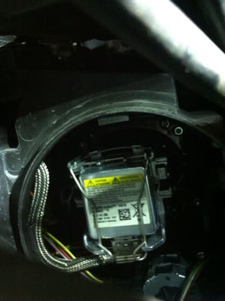 This is a view of the HID light from behind the headlight housing.  There are two tension spring wire clips holding the HID headlight ballast/base.