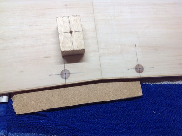 Marking out where the lower wing mounting holes need to be. Wood block drilled in drill press is used as drill guide.