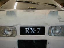 Custom RX7 plate I made
Consists of pleiglass.
Had the RX7 stickers cut in reverse, stock them to the back side of the plexi, sprayed it black, pealed the stickers off, placed mirror tape to the back panel behined the plexi, placed 4 red Varad LED's back there, then fiberglassed the plexi in place.
Looks good lit up @ night..