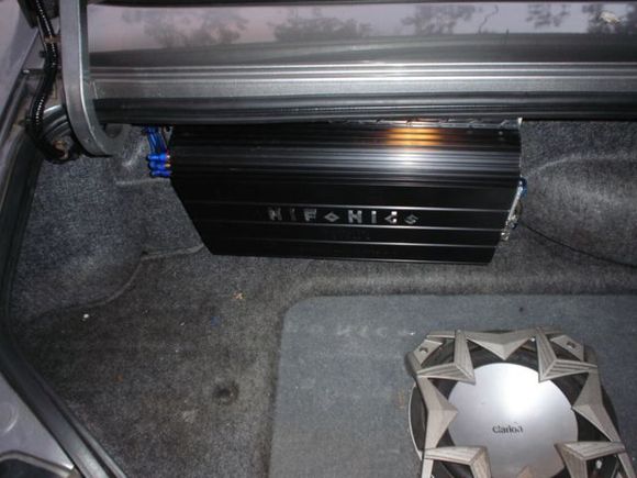 Amp on rear wall of trunk, left of spare