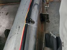 Black bracket welded to trans tunnel anchors front cable housing.